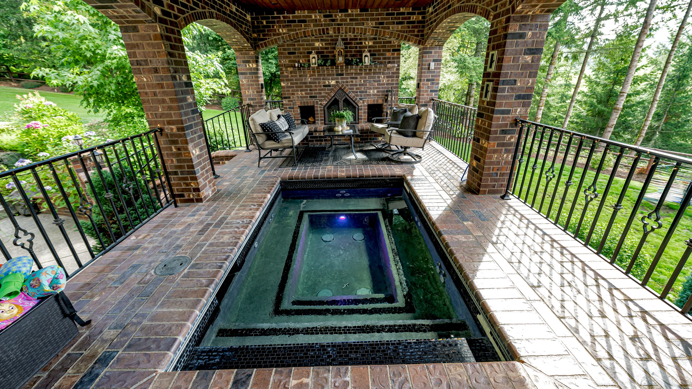 Brown brick envelopes this outdoor living space with hot tub and fireplace