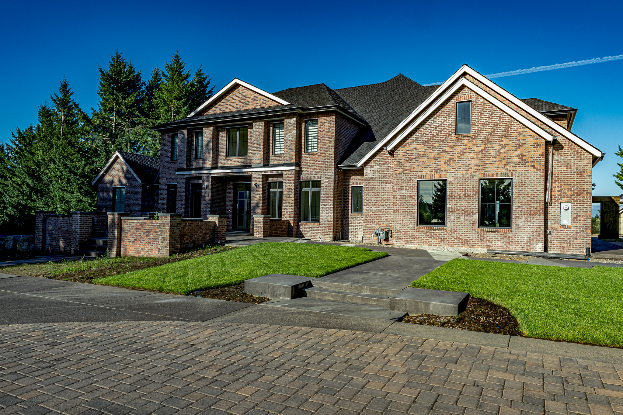 A brick house fronted by a concrete paver driveway.