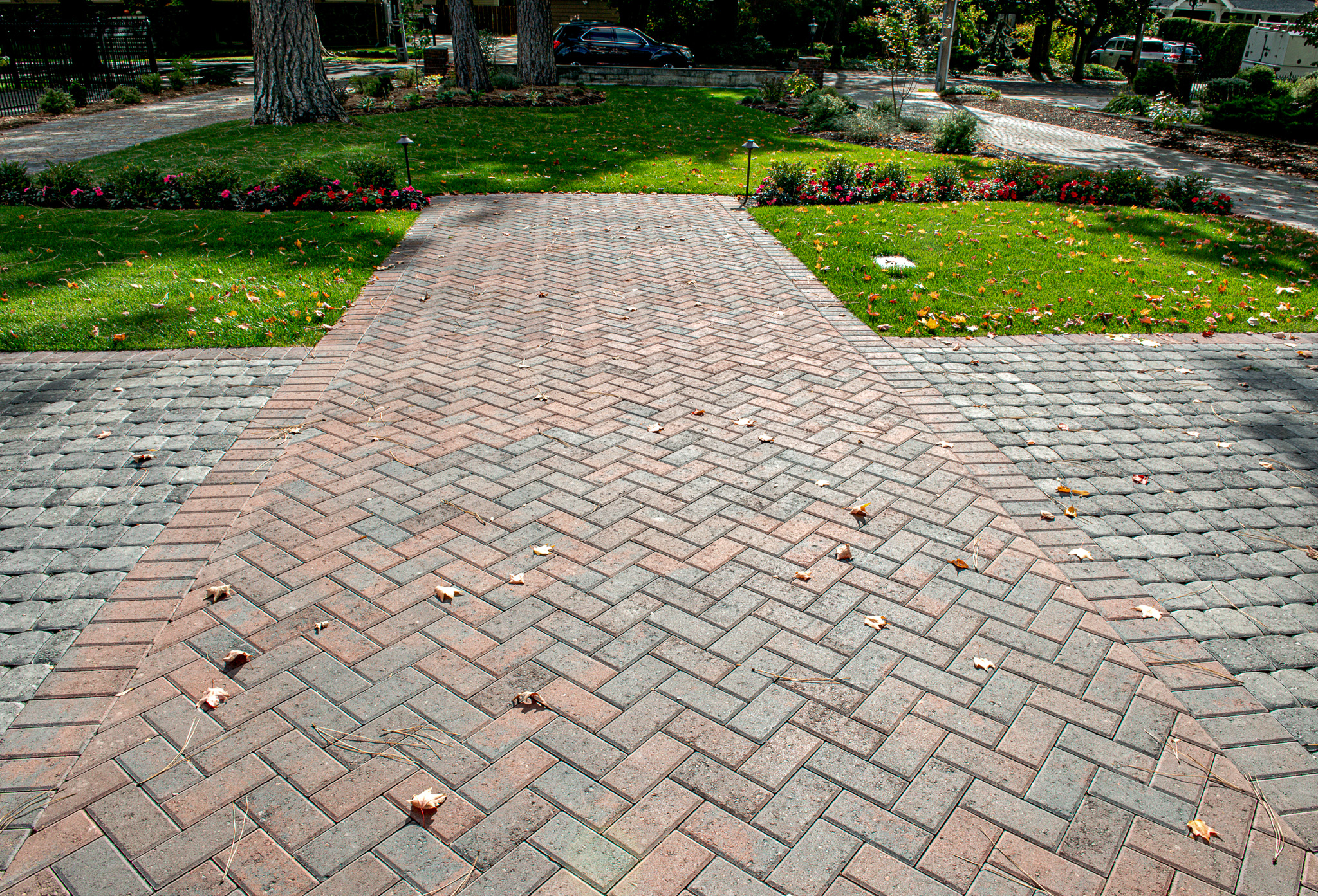 Red concrete pavers bisect a gray concrete paver driveway